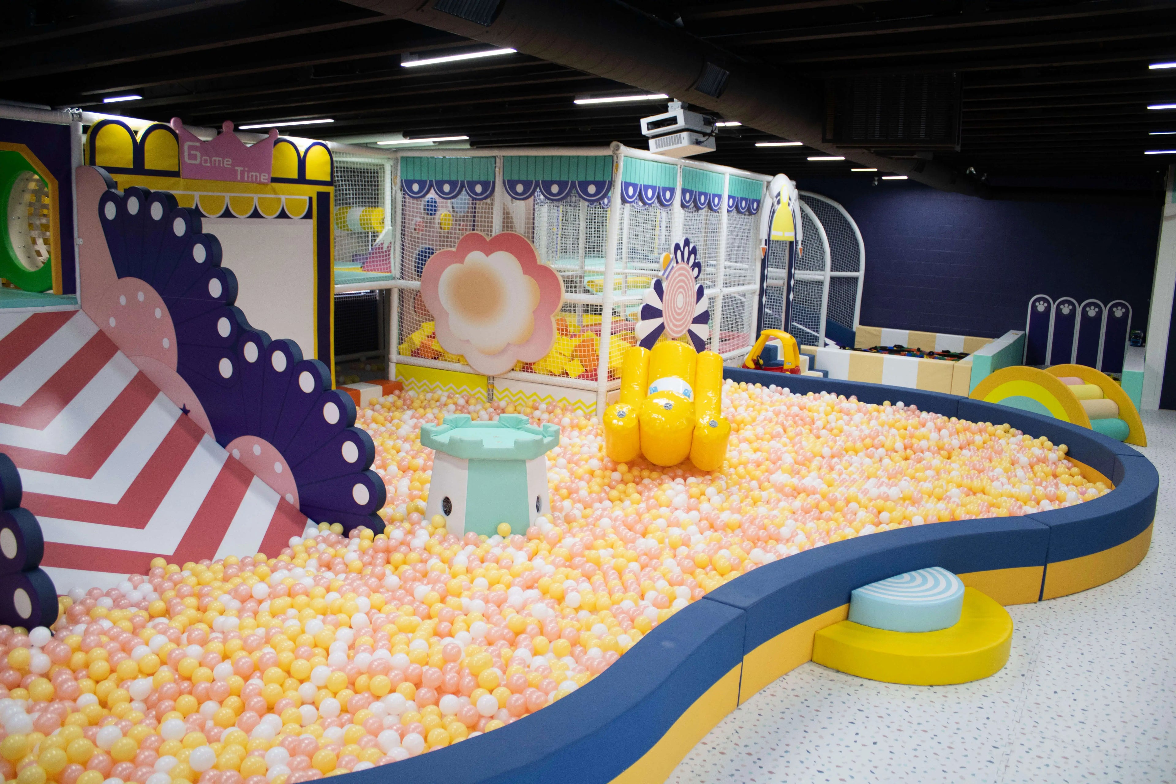 Colorful indoor playground at Kool Kids Club LA featuring a pastel ball pit, slides, and interactive play structures for kids.